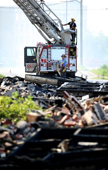 Firefighters seen behind piles of debris work a warehouse fire on Jarvis Avenue on Mon., July 22, 2019. Kevin King/Winnipeg Sun/Postmedia Network