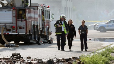 Jason Shaw (left), assistant chief of Emergency Management and Public Information, walks communications officer Erin Madden (centre) and an unidentified woman through the scene of a warehouse fire on Jarvis Avenue on Mon., July 22, 2019. Kevin King/Winnipeg Sun/Postmedia Network