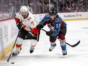 T.J. Brodie of the Calgary Flames fights on the boards with Gabriel Bourque of the Colorado Avalanche in the third period during Game 3 of the Western Conference First Round during the 2019 NHL Stanley Cup Playoffs at the Pepsi Center in Denver on April 15.