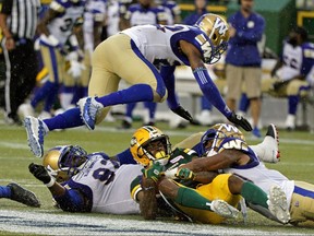 Winnipeg Blue Bombers Chandler Fenner leaps over Edmonton Eskimos Ricky Collins Jr. (middle) after he is tackled by Bombers Drake Nevis (left) and Marcus Rios (right) during Canadian Football League game action in Edmonton on Friday August 23, 2019. (PHOTO BY LARRY WONG/POSTMEDIA)