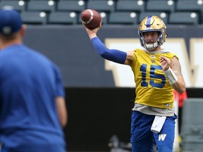 Winnipeg Blue Bombers quarterback Matt Nichols (right) dumps a pass off to running back Andrew Harris while under pressure from the Calgary Stampeders during CFL action in Winnipeg on Thursday.