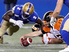 Winnipeg Blue Bombers defensive end Jonathan Kongbo (left) cannot beat B.C. Lions quarterback Mike Reilly to a fumble after a sack during CFL action in Winnipeg on Thurs., Aug. 15, 2019. Kevin King/Winnipeg Sun/Postmedia Network