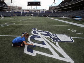 Laurel Gray paints an NFL logo onto IG Field in Winnipeg on Wed., Aug. 21, 2019 in advance of Thursday's NFL exhibition clash between the Oakland Raiders and the Green Bay Packers. Kevin King/Winnipeg Sun/Postmedia Network