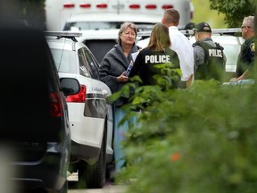 A woman wrapped in a blanket speaks with police officers in the backlane of the scene of a serious incident on Overdale Street in Winnipeg on Monday.