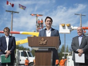 Minister of Fisheries, Oceans and the Canadian Coast Guard, Jonathan Wilkinson, left, and British Columbia Premier John Horgan, right, look on as Prime Minister Justin Trudeau makes an announcement at BC Hydro Trades Training Centre in Surrey, B.C., Thursday, August, 29, 2019.