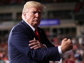 U.S. President Donald Trump pats his bicep and pumps his fist at the end of his rally with supporters in Manchester, New Hampshire, U.S. August 15, 2019.