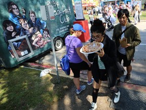 A woman chows down on pizza as she heads for the beer gardens to find a seat during ManyFest in downtown Winnipeg on Sun., Sept. 9, 2018. Kevin King/Winnipeg Sun/Postmedia Network