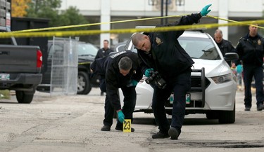 Forensic officers place evidence markers at the scene of a shooting in the backlane of the 200 blocks of Smith and Garry streets, near the Winnipeg Police Service headquarters, in Winnipeg on Thurs., Sept. 12, 2019. Kevin King/Winnipeg Sun/Postmedia Network