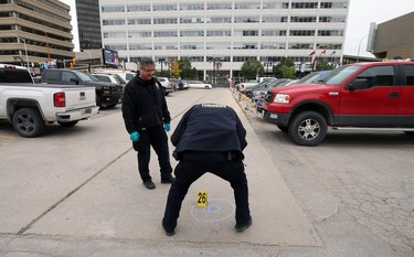 Forensic officers collect evidence at the scene of a shooting in the backlane of the 200 blocks of Smith and Garry streets in Winnipeg on Thurs., Sept. 12, 2019. The Winnipeg Police Service headquarters is in the background. Kevin King/Winnipeg Sun/Postmedia Network