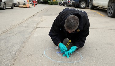 A forensics officer collects a spent round at the scene of a shooting in the backlane of the 200 blocks of Smith and Garry streets in Winnipeg on Thurs., Sept. 12, 2019. Kevin King/Winnipeg Sun/Postmedia Network