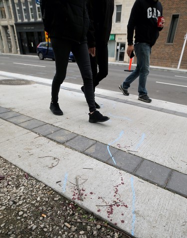 Pedestrians pass a trail of blood that extends from the  backlane of the 200 blocks of Smith and Garry streets and out onto Garry Street after a shooting in the backlane on Thurs., Sept. 12, 2019. Kevin King/Winnipeg Sun/Postmedia Network