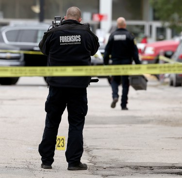 Forensic officers collect evidence at the scene of a shooting in the backlane of the 200 blocks of Smith and Garry streets in Winnipeg on Thurs., Sept. 12, 2019. Winnipeg police headquarters is in the background. Kevin King/Winnipeg Sun/Postmedia Network
