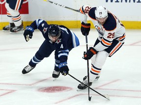 Winnipeg Jets defenceman Neal Pionk (left) pokes the puck away from Edmonton Oilers centre Leon Draisaitl during NHL pre-season action at Bell MTS Place in Winnipeg on Thurs., Sept. 26, 2019. Kevin King/Winnipeg Sun/Postmedia Network