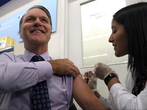 Manitoba Health minister Cameron Friesen is given a flu shot during the department's kick off to their flu shot campaign at a Shoppers Drug Mart at Grant Park in Winnipeg in October. According to the province's latest influenza surveillance report, Manitoba has recorded 15 deaths from the flu since September.