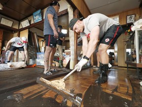 Canada's national rugby union team player Peter Nelson and other teammates help remove mud inside a house at a flooded area, caused by Typhoon Hagibis in Kamaishi, Iwate prefecture, Japan Oct. 13, 2019. (Kyodo via REUTERS)