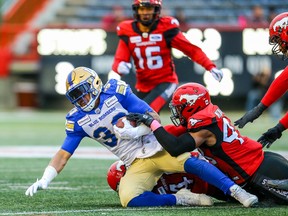 Bombers running back Andrew Harris is brought down by the Calgary defence at McMahon Stadium last night. (Al Charest/Postmedia)