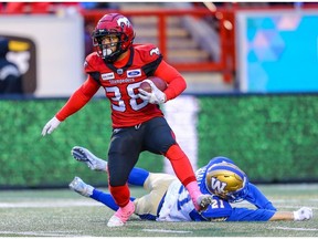 Calgary Stampeders Terry Williams avoids a tackle by Nick Hallett Winnipeg Blue Bombers during CFL football in Calgary on Saturday.
