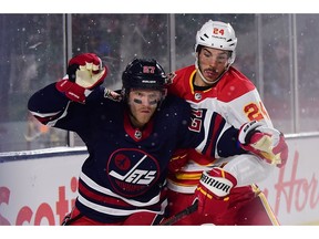 Oct 26, 2019; Regina, Saskatchewan, CAN; Winnipeg Jets forward Nikolaj Ehlers (27) battles for the puck against Calgary Flames defenseman Travis Hamonic (24) during the second period of the 2019 Heritage Classic outdoor hockey game at Mosaic Stadium. Mandatory Credit: Anne-Marie Sorvin-USA TODAY Sports ORG XMIT: USATSI-405162