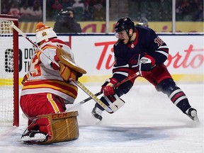 Winnipeg Jets forward Bryan Little (18) scores against Calgary Flames goaltender David Rittich (33) during overtime of the 2019 Heritage Classic outdoor hockey game at Mosaic Stadium in Regina on Saturday night.