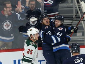 Jets’ Jack Roslovic (left) celebrates his third-period goal against the Minnesota Wild on Thursday night alongside teammate Josh Morrissey. The Jets have three wins in five games and take on the Blackhawks in Chicago on Saturday. (KEVIN KING/WINNIPEG SUN)