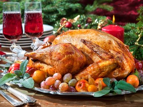 Roasted turkey on holiday table, candles and Christmas tree with ornaments