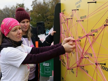 A woman ties a piece of yarn onto the Threads of Connection board, meant to illustrate peer support, during the 28th annual Run for the Cure event for the Canadian Cancer Society, at Shaw Park in Winnipeg on Sun., Oct. 6, 2019. Kevin King/Winnipeg Sun/Postmedia Network