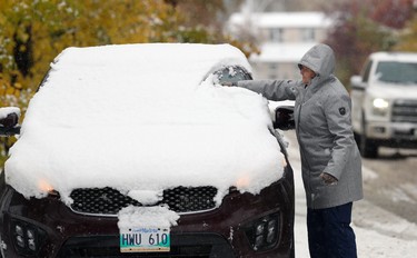 Katina (last name withheld by request) uses her arm to clear snow off her vehicle on Ubique Crescent in the Tuxedo area of Winnipeg on Thurs., Oct. 10, 2019. Kevin King/Winnipeg Sun/Postmedia Network