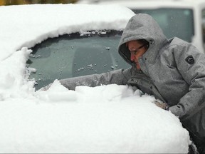 Katina (last name withheld by request) uses her arm to clear snow off her vehicle on Ubique Crescent in the Tuxedo area of Winnipeg on Thurs., Oct. 10, 2019. Kevin King/Winnipeg Sun/Postmedia Network