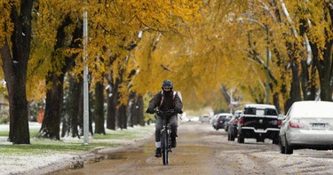 A man with tennis gear on his back cycles down Borebank Avenue in the River Heights area of Winnipeg on Thurs., Oct. 10, 2019. Kevin King/Winnipeg Sun/Postmedia Network