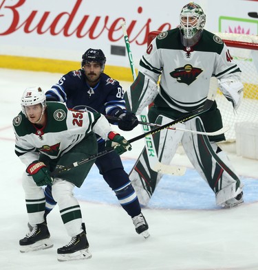 Winnipeg Jets forward Mathieu Perreault (centre) fights for space in front of Minnesota Wild goaltender Devan Dubnyk with defenceman Jonas Brodin during NHL action in Winnipeg on Thurs., Oct. 10, 2019. Kevin King/Winnipeg Sun/Postmedia Network