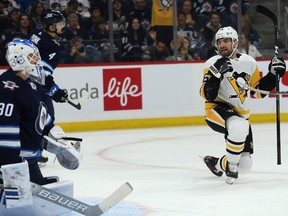 Pittsburgh Penguins centre Zach Aston-Reese (right) celebrates his first-period goal past Winnipeg Jets goaltender Laurent Brossoit during NHL action in Winnipeg on Sunday.