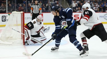 Winnipeg Jets centre Mark Scheifele throws a backhand pass through the crease with Phoenix Coyotes forward Phil Kessel defending during NHL action in Winnipeg on Tues., Oct. 15, 2019. Kevin King/Winnipeg Sun/Postmedia Network
