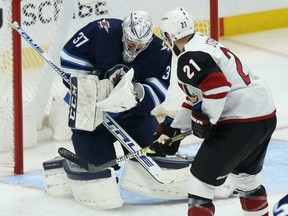 Winnipeg Jets goaltender Connor Hellebuyck holds the puck with Phoenix Coyotes centre Derek Stepan waiting for a rebound during NHL action in Winnipeg on Tues., Oct. 15, 2019. Kevin King/Winnipeg Sun/Postmedia Network