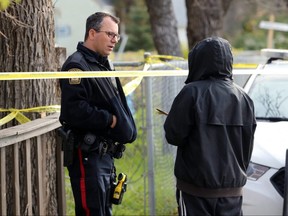 A teenager who said he knew the victim asks a police officer if he can leave an offering in an apartment building at 345 Talbot Avenue, the scene of a fatal stabbing, in Winnipeg on Wed., Oct. 23, 2019. A feather, braid of sweetgrass and a cigarette were left nearby. Kevin King/Winnipeg Sun/Postmedia Network