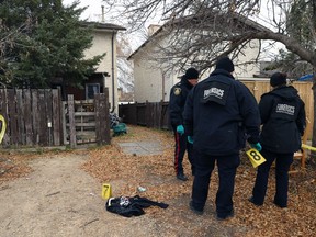 Forensics officers investigate in the back yard of a residence in the 100 block of Kinver Avenue in Winnipeg on Sunday. A 14-year-old girl was killed and an 18-year-old is in hospital in stable condition after they were stabbed.