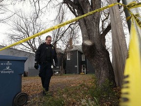 A forensics officer investigates in the rear lane of Ross Avenue in Winnipeg on Sunday. Two adult males were killed in the lane during the early morning hours.