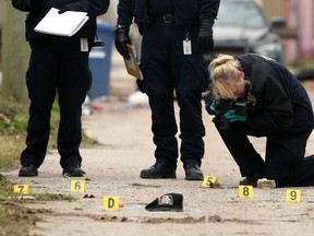 Forensics officers collect evidence in the rear lane of Ross Avenue in Winnipeg on Sun., Oct. 27, 2019. Two adult males were killed in the lane during the early morning hours. Kevin King/Winnipeg Sun/Postmedia Network