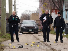 Forensics officers collect evidence in the rear lane of Ross Avenue in Winnipeg on Sunday. Two adult males were killed in the lane during the early morning hours.