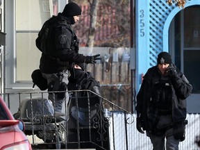 A tactical team member signals that he has two people coming out of a multi-unit dwelling that is the scene of an apparent armed and barricaded incident on Pacific Avenue between Ellen and Paulin streets in Winnipeg on Thurs., Oct. 31, 2019. A man and woman got into a vehicle and drove away. An armoured vehicle was on scene, as well as a police negotiator and an ambulance on standby for what police say came in as an armed robbery call just before 5 a.m. on Thursday morning. Officers could be heard using a megaphone asking people inside the home to come out with their arms in the air. Kevin King/Winnipeg Sun/Postmedia Network