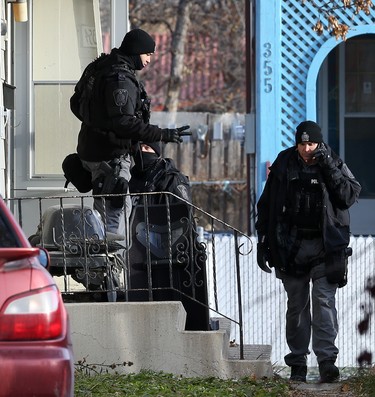 A tactical team member signals that he has two people coming out of a multi-unit dwelling that is the scene of an apparent armed and barricaded incident on Pacific Avenue between Ellen and Paulin streets in Winnipeg on Thurs., Oct. 31, 2019. A man and woman got into a vehicle and drove away. An armoured vehicle was on scene, as well as a police negotiator and an ambulance on standby for what police say came in as an armed robbery call just before 5 a.m. on Thursday morning. Officers could be heard using a megaphone asking people inside the home to come out with their arms in the air. Kevin King/Winnipeg Sun/Postmedia Network