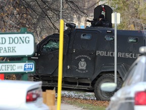 A tactical team member trains a weapon at a multi-unit dwelling that is the scene of an apparent armed and barricaded incident on Pacific Avenue between Ellen and Paulin streets in Winnipeg on Thursday.