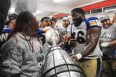 CALGARY, AB - NOVEMBER 24: Andrew Harris #33 (C) and Stanley Bryant #66 of the Winnipeg Blue Bombers drink champagne from the Grey Cup after defeating the Hamilton Tiger-Cats during the 107th Grey Cup Championship Game at McMahon Stadium on November 24, 2019 in Calgary, Alberta, Canada. (Photo by Derek Leung/Getty Images)