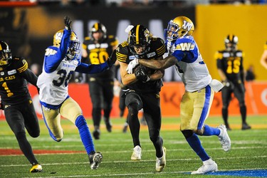 CALGARY, AB - NOVEMBER 24: Jaelon Acklin #80 of the Hamilton Tiger-Cats runs the ball against Brandon Alexander #37 (R) and Winston Rose #30 of the Winnipeg Blue Bombers during the 107th Grey Cup Championship Game at McMahon Stadium on November 24, 2019 in Calgary, Alberta, Canada. (Photo by Derek Leung/Getty Images)