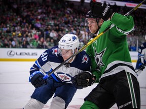 Jets’ Joona Luoto (left) and Stars’ Corey Perry fight for the puck Thursday night in Dallas. (USA TODAY SPORTS)