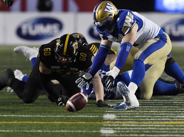 Nov 24, 2019; Calgary, Alberta, CAN; Winnipeg Blue Bombers linebacker Adam Bighill (4) recovers a fumble ahead of Hamilton Tiger-Cats offensive lineman Darius Ciraco (60) in the first half during the 107th Grey Cup championship football game at McMahon Stadium. Mandatory Credit: Eric Bolte-USA TODAY Sports ORG XMIT: USATSI-408191