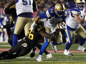 Winnipeg Blue Bombers running back Andrew Harris (33) runs the ball against Hamilton Tiger-Cats defensive back Cariel Brooks (26) in the second half during the 107th Grey Cup championship football game at McMahon Stadium in Calgary on Nov 24, 2019.