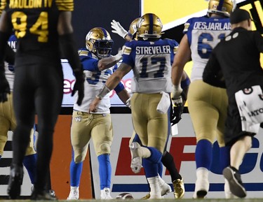 Nov 24, 2019; Calgary, Alberta, CAN; Winnipeg Blue Bombers running back Andrew Harris (33) celebrates with quarterback Chris Streveler (17) after scoring a touchdown against the Hamilton Tiger-Cats in the first half during the 107th Grey Cup championship football game at McMahon Stadium. Mandatory Credit: Eric Bolte-USA TODAY Sports