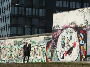 A couple walk past original sections of the former Berlin Wall at the East Side Gallery on the day before the 25th anniversary of German reunification on Oct. 2, 2015 in Berlin. (Sean Gallup/Getty Images)