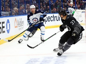 Nov 16, 2019; Tampa, FL, USA; Winnipeg Jets defenseman Neal Pionk (4) passes the puck as Tampa Bay Lightning center Yanni Gourde (37) defends during the first period at Amalie Arena. Mandatory Credit: Kim Klement-USA TODAY Sports