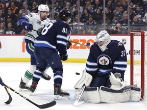 Winnipeg Jets defenceman Nathan Beaulieu (88) defends as Vancouver Canucks center Tim Schaller (59) looks for a rebound in front of Winnipeg Jets goaltender Connor Hellebuyck (37) in the first period at Bell MTS Place on Friday.